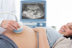 Male OBGYN Doctor Performing Ultrasound on Pregnant Female Patient at OBGYN Office