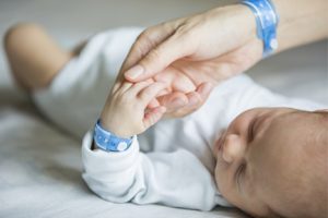Young Mom Kissing the Cheek of Her Newborn Baby After OBGYN Appointment